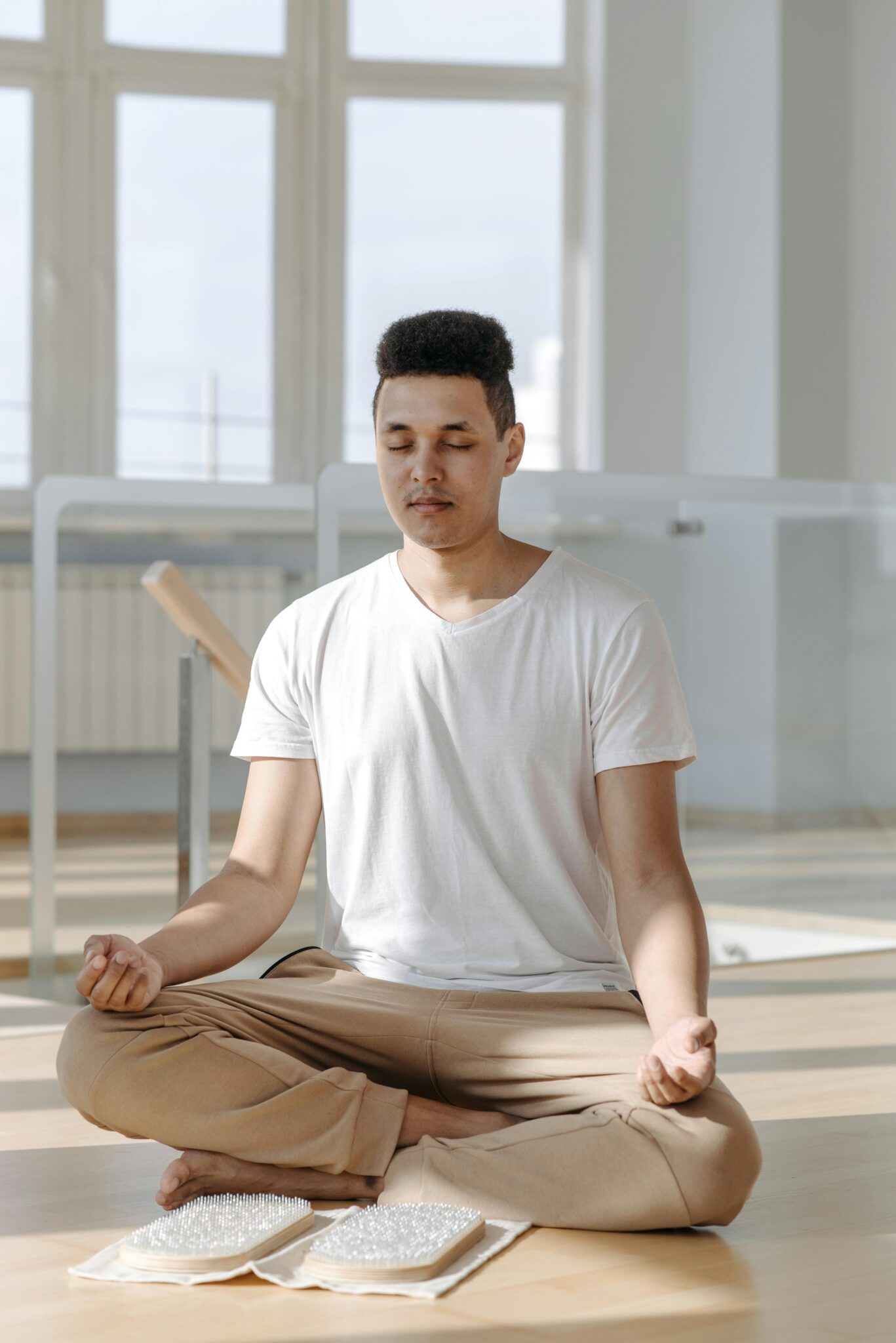 A young man meditates in a bright and serene indoor space, embodying relaxation.