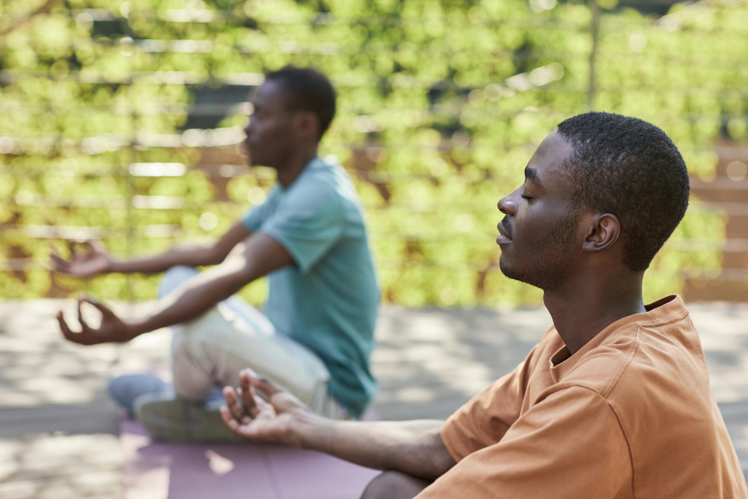 Two men meditating outdoors, capturing a sense of relaxation and mindfulness.